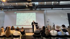Talare vid podium inför elever under ett skolbesök i Växjö.