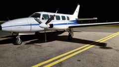 Ett flygplan står parkerat på en landningsbana nattetid.