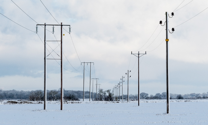 Snötäckt elnät i ett vinterlandskap.