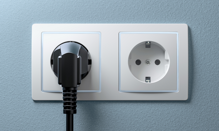 En kontakt är isatt i ett av två eluttag på en vägg.