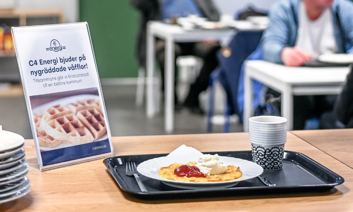 Cafébord med en tallrik våfflor och skylten "C4 Energi bjuder på nygräddade våfflor".