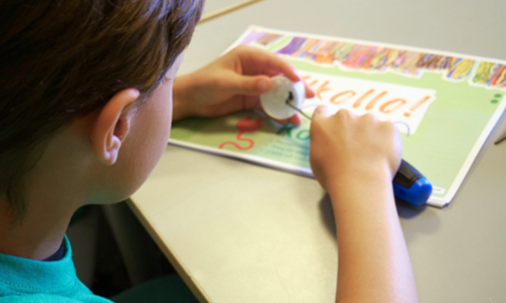 Ett barn arbetar med en elektronisk krets på ett papper.