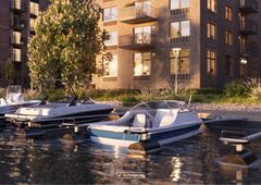 Bostadshus vid vattnet i Bryggudden, Karlstad, med båtar vid bryggan i kvällsljus.