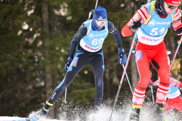 Två längdskidåkare tävlar i skogen.