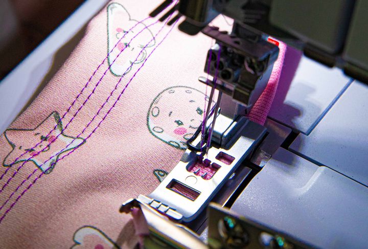 Symaskin syr på rosa tyg med stjärnor och månar.