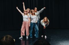 En grupp elever i dansklass på scen som poserar