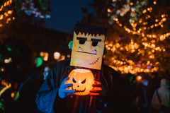 Utklädd deltagare med Frankensteinmask håller en lysande pumpa.