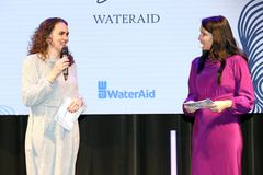Bild på två kvinnor som står på en scen och pratar i mikrofoner vid ett WaterAid-evenemang.