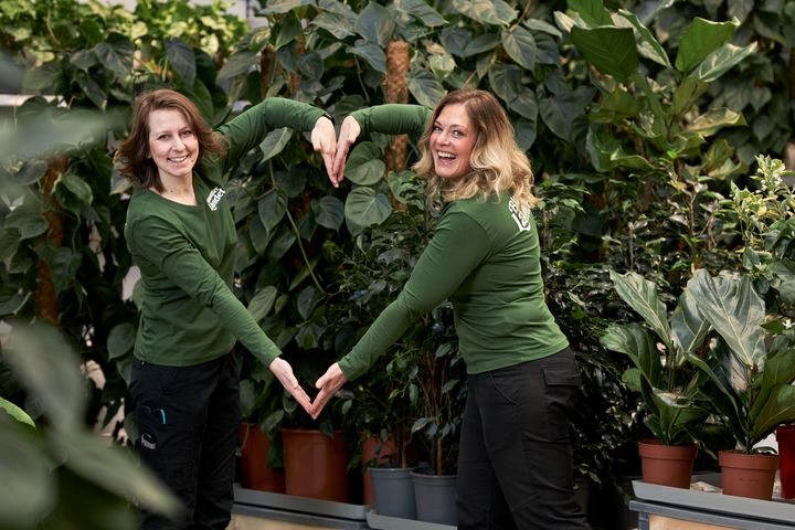 Blomstermedarbetare-står-i-butik-och-formar-ett-hjärta-med-sina-armar