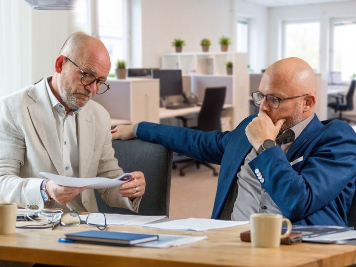 Johan Zetterstedt och Pär Johansson och arbetar vid ett bord med dokument och kaffekoppar.