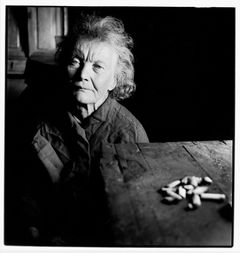 Svartvit bild av äldre kvinna som sitter i mörkt rum.