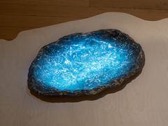 Skulptur som liknar en upplyst vattensamling med blått ljus.