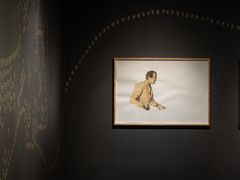 Konstverk av Maria Kapajeva på mörk bakgrund med en ramad bild av en person. Små detaljer eller mönster syns på väggen till vänster.