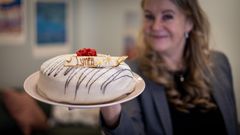 Kvinna håller en tårta med texten "Lynea".