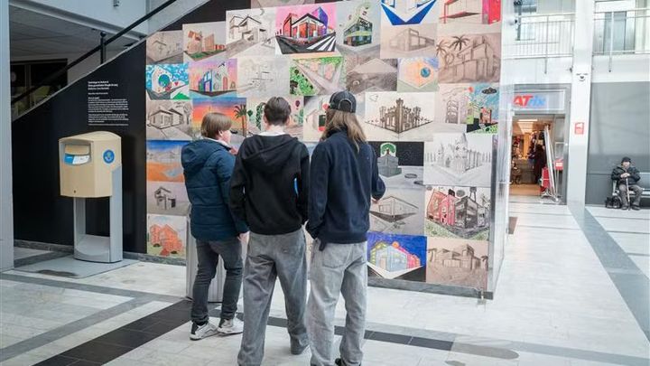 Ungdomar tittar på teckningar som sitter på en vägg.