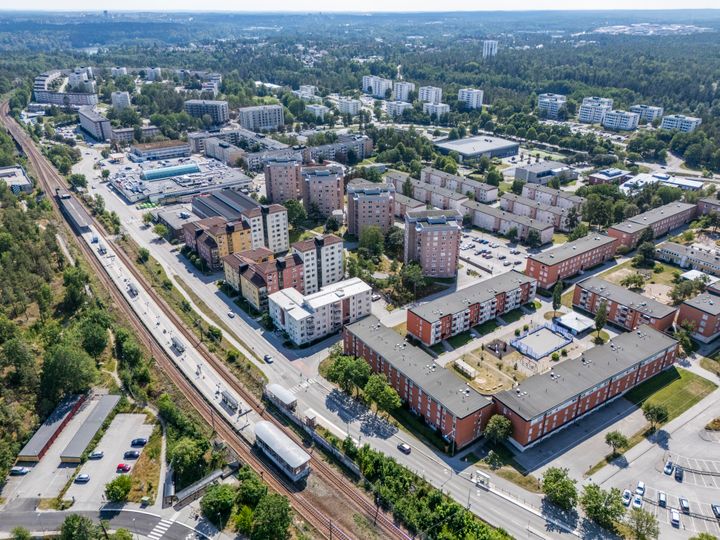Flygfoto över ett bostadsområde i Skogås med flerfamiljshus och omgivande grönområden.