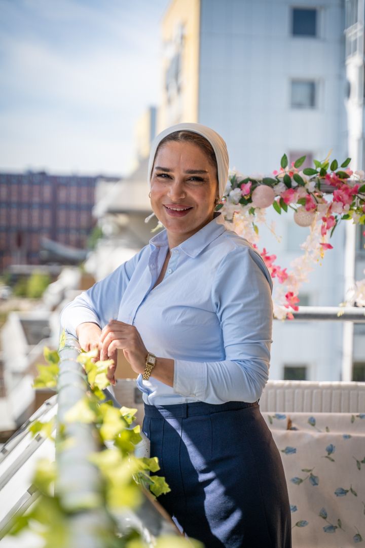 Maissa Jalloul står leende på sin blomsterprydda balkong i Flemingsberg.