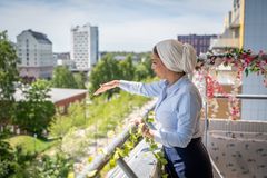 En kvinna står på en balkong och pekar ner mot marken