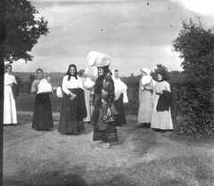 Ett fotografi från 1917 har legat till grund för vårt arbete med den här utställningen. I bildens mitt står Johanna Lovisa Persdotter från Boasten med skorna i hand, på väg att lämna över vävda textilier till förläggaren. Det sägs att hon gått de fem kilometrarna till Amundagärde barfota för att spara på sina skor, och sedan glömt att ta dem på sig innan fotografiet togs. Hennes bara fötter, kvinnornas kroppshållning och kläder, vittnar om arbetslivets hårda villkor och den sociala gemenskap som växte fram kring textil- och hemindustrin.