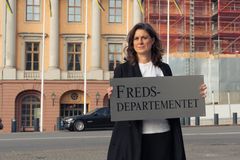 Svenska Freds ordförande Kerstin Bergeå med en Fredsdepartementskylt utanför UD