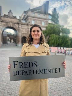 Svenska Freds ordförande Kerstin Bergeå med Fredsdepartementskylt, stående bild