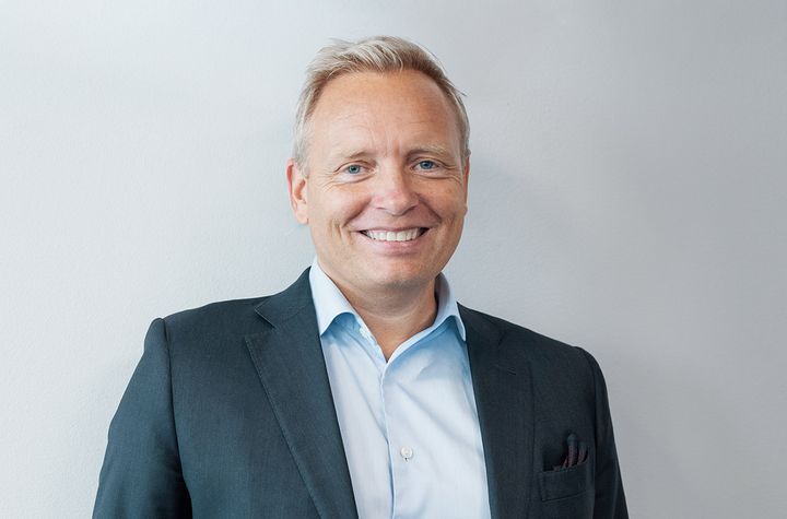 En man i kostym som ler mot kameran.