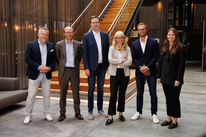 En grupp människor poserar framför en trappa i en modern byggnad.