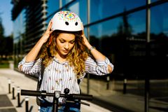 ung kvinna som sätter på sig hjälmen innan hon kör iväg på elsparkcykeln