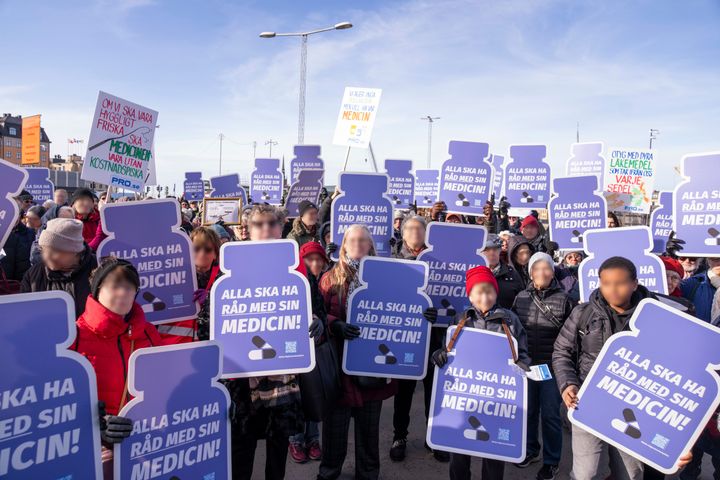 Deltagare vid en demonstration på Mynttorget i Stockholm håller upp skyltar mot höjda medicinkostnader.