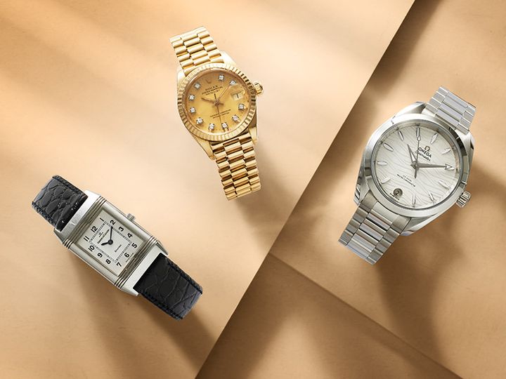 Tre klockor på en beige bakgrund: en guldfärgad klocka med diamanter, en rektangulär klocka med svart läderarmband, och en silverfärgad klocka.