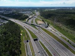 Flygbild över trafikplats Häggvik med motorvägar, bilar och omgivande skog.