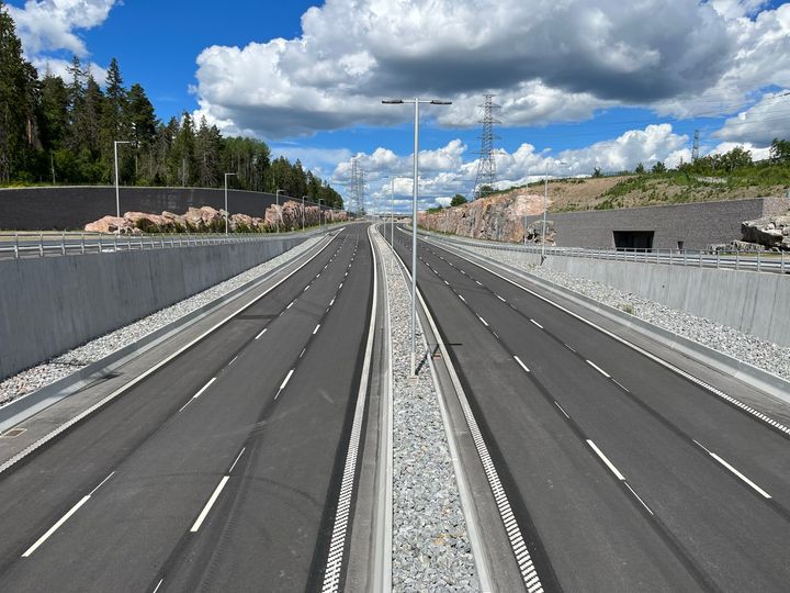 Nybyggd motorväg vid Akalla, Förbifart Stockholm, under blå himmel med vita moln.