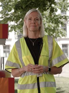 Kvinna i reflexväst med Trafikverkets logotyp som står utomhus.