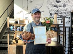 Glad vinnare med diplom, blommor och kanelbullar